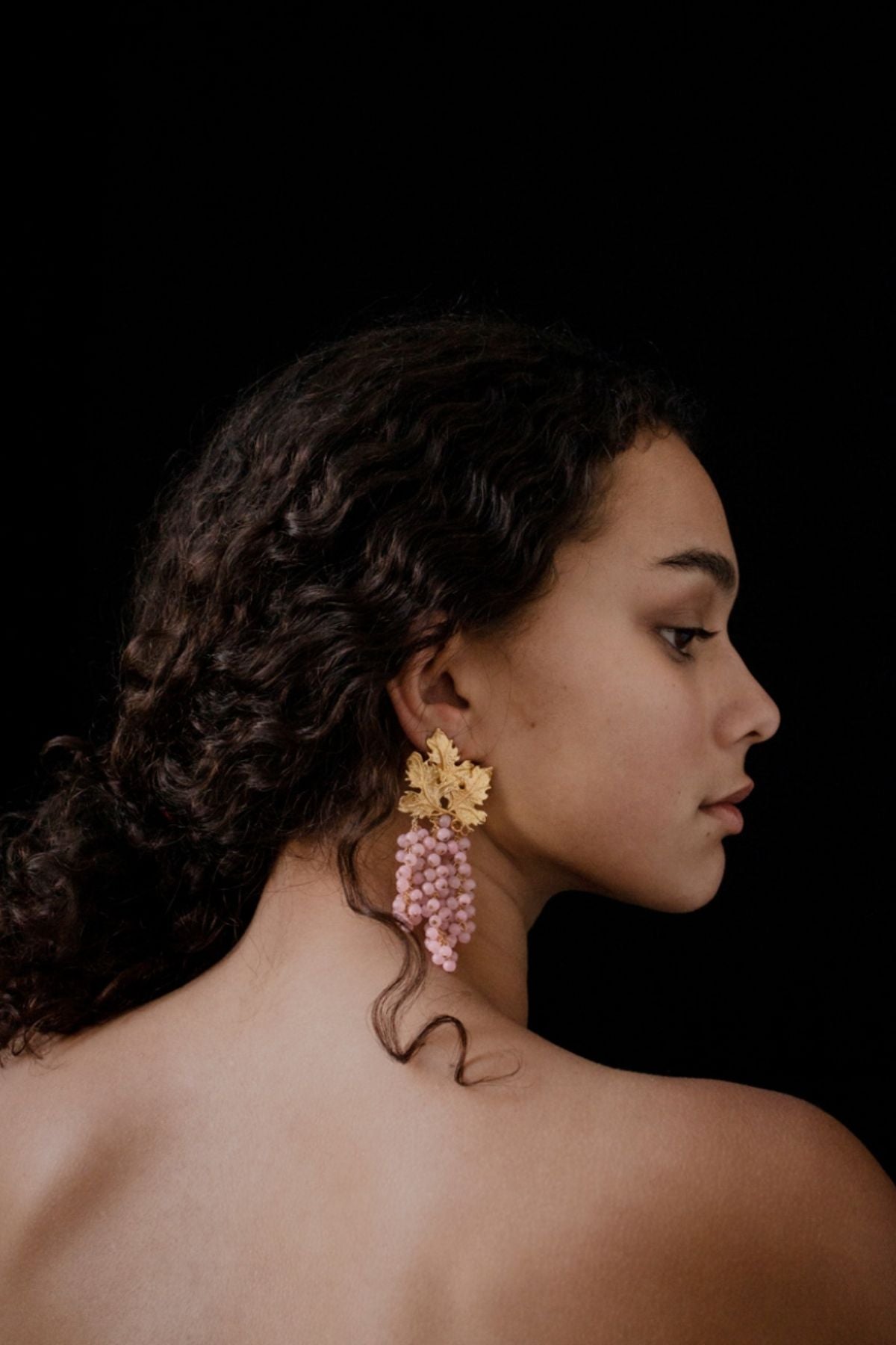 Woman wearing colorful earrings against a black background