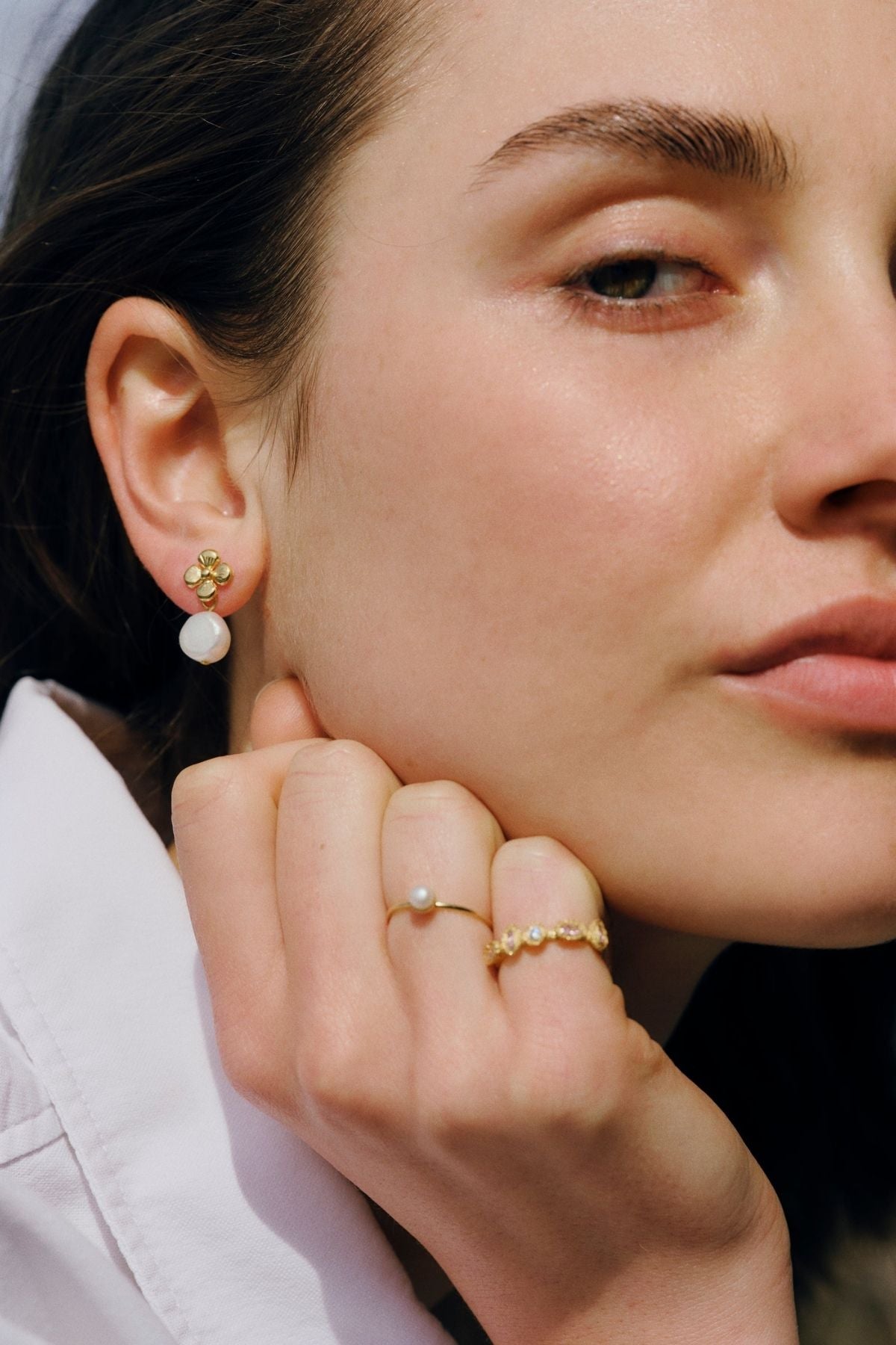 Close-up of a woman wearing gold earrings and rings with a blurred background