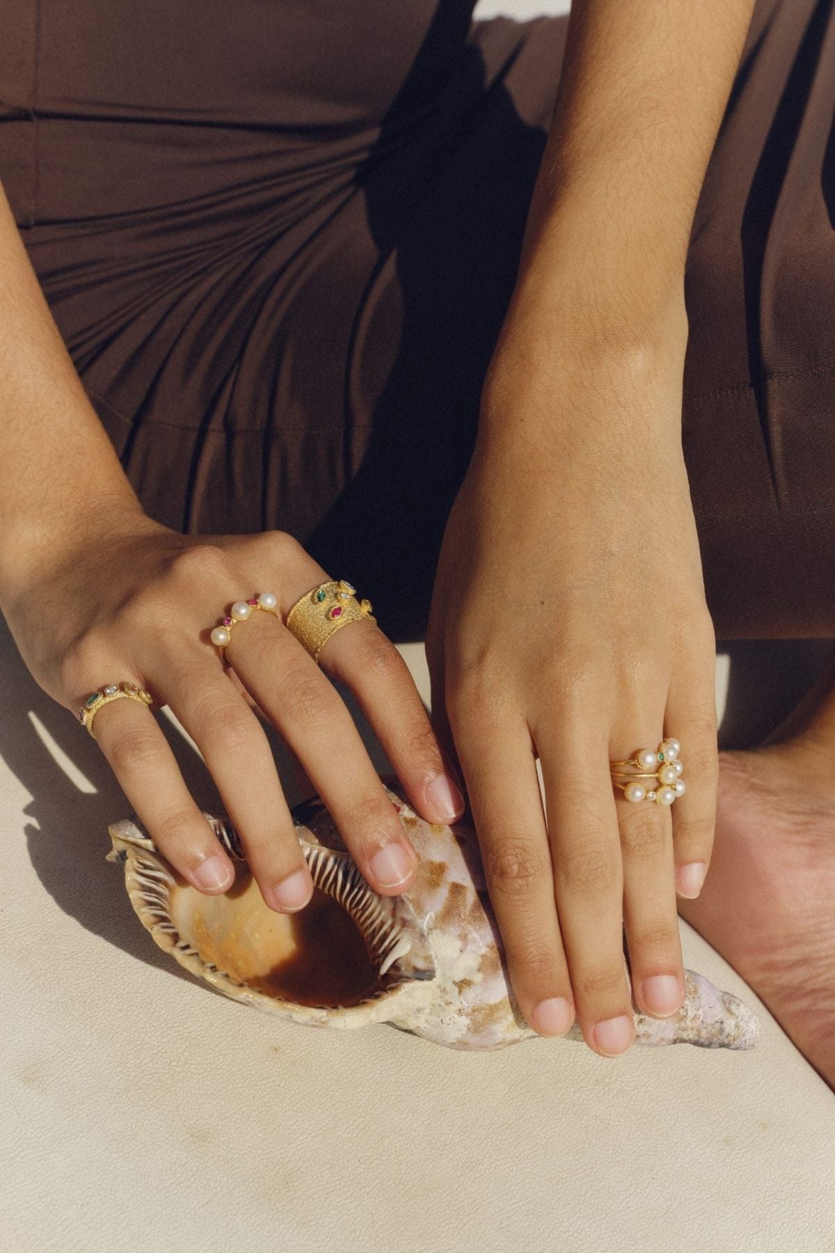 Close-up of hands with gold rings on a neutral background
