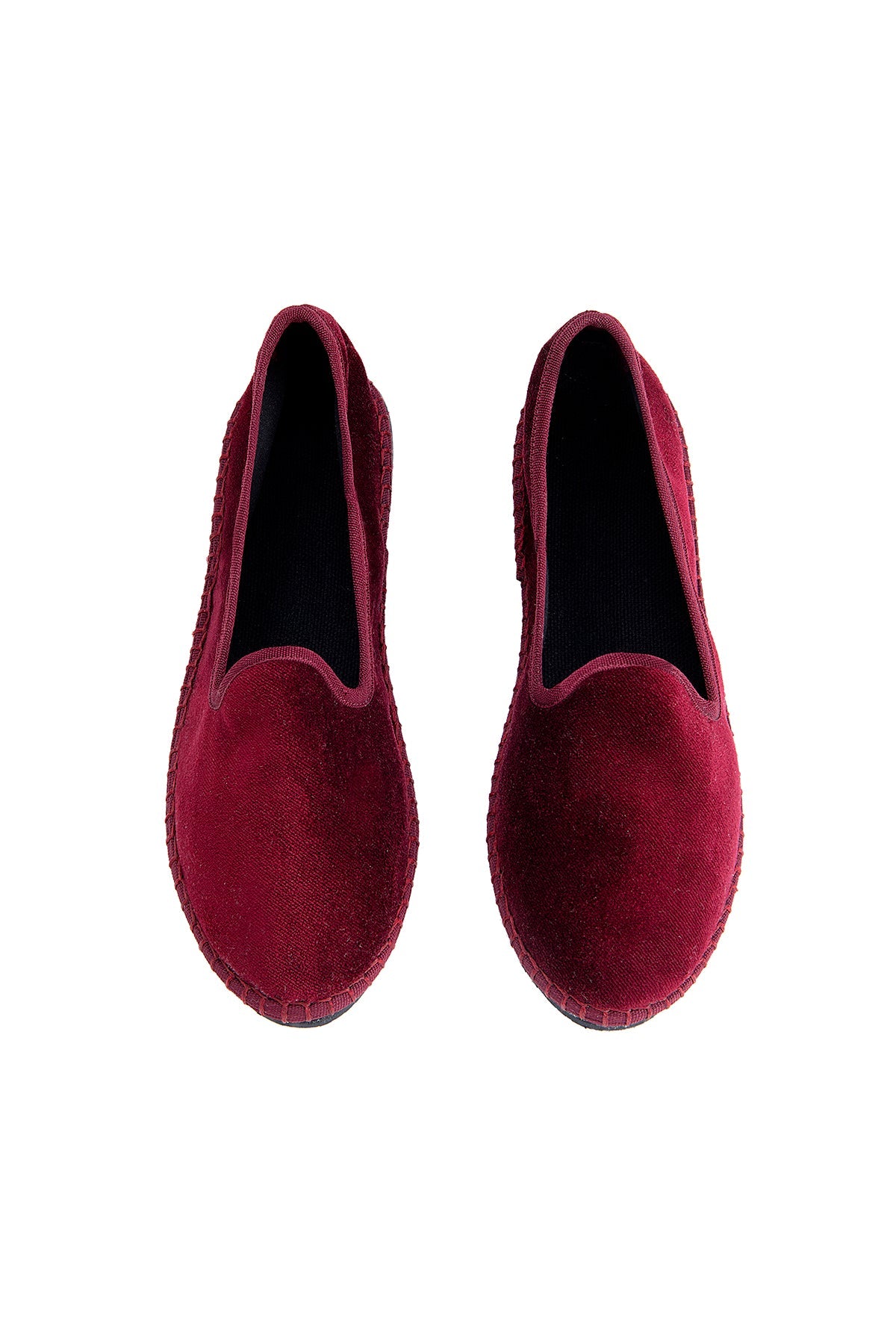 Pair of maroon velvet loafers on a white background