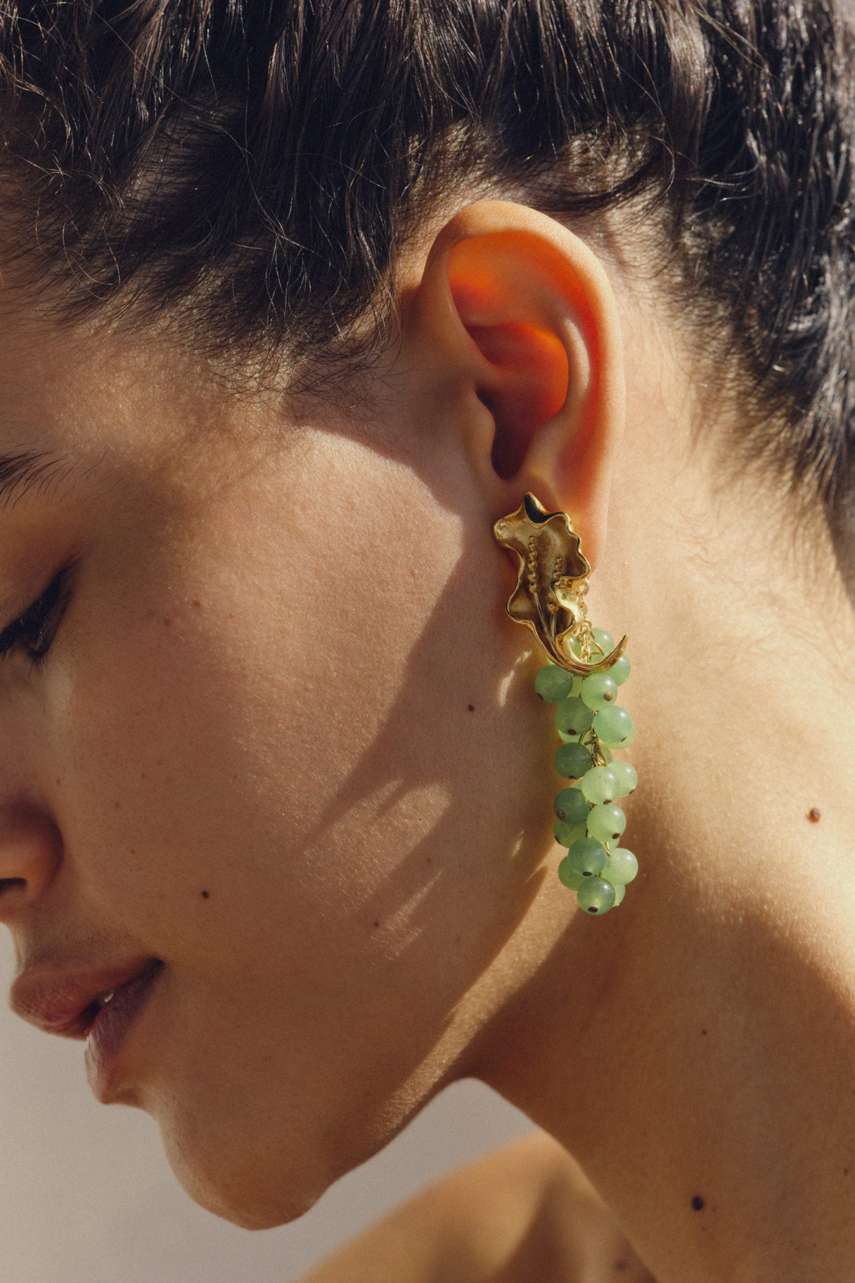 Close-up of a person wearing a green earring with a gold star design.