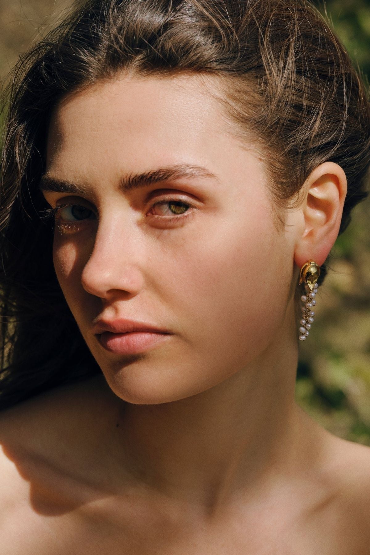 Close-up of a woman wearing earrings with a blurred natural background