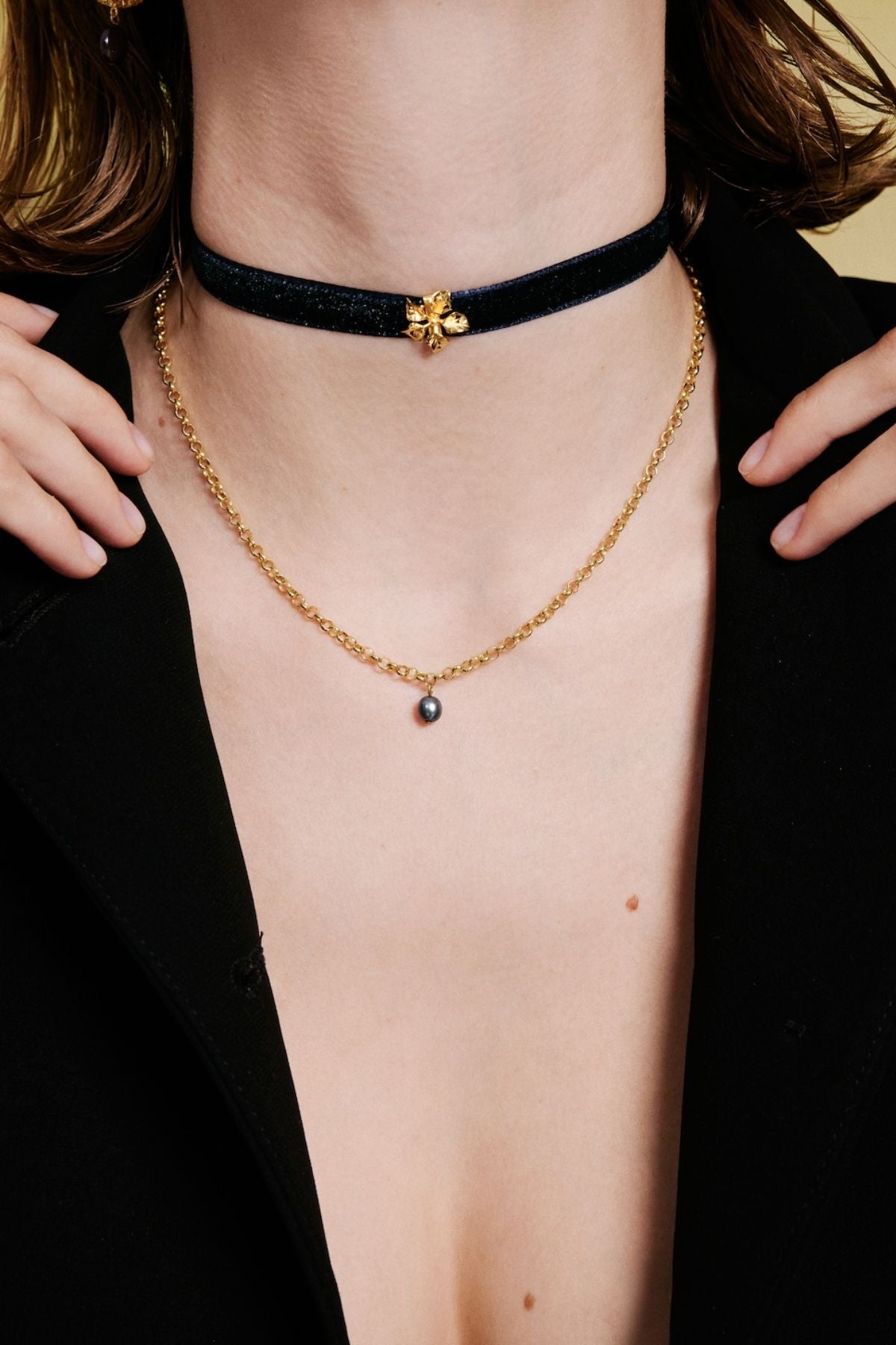Person wearing a gold necklace with a black choker