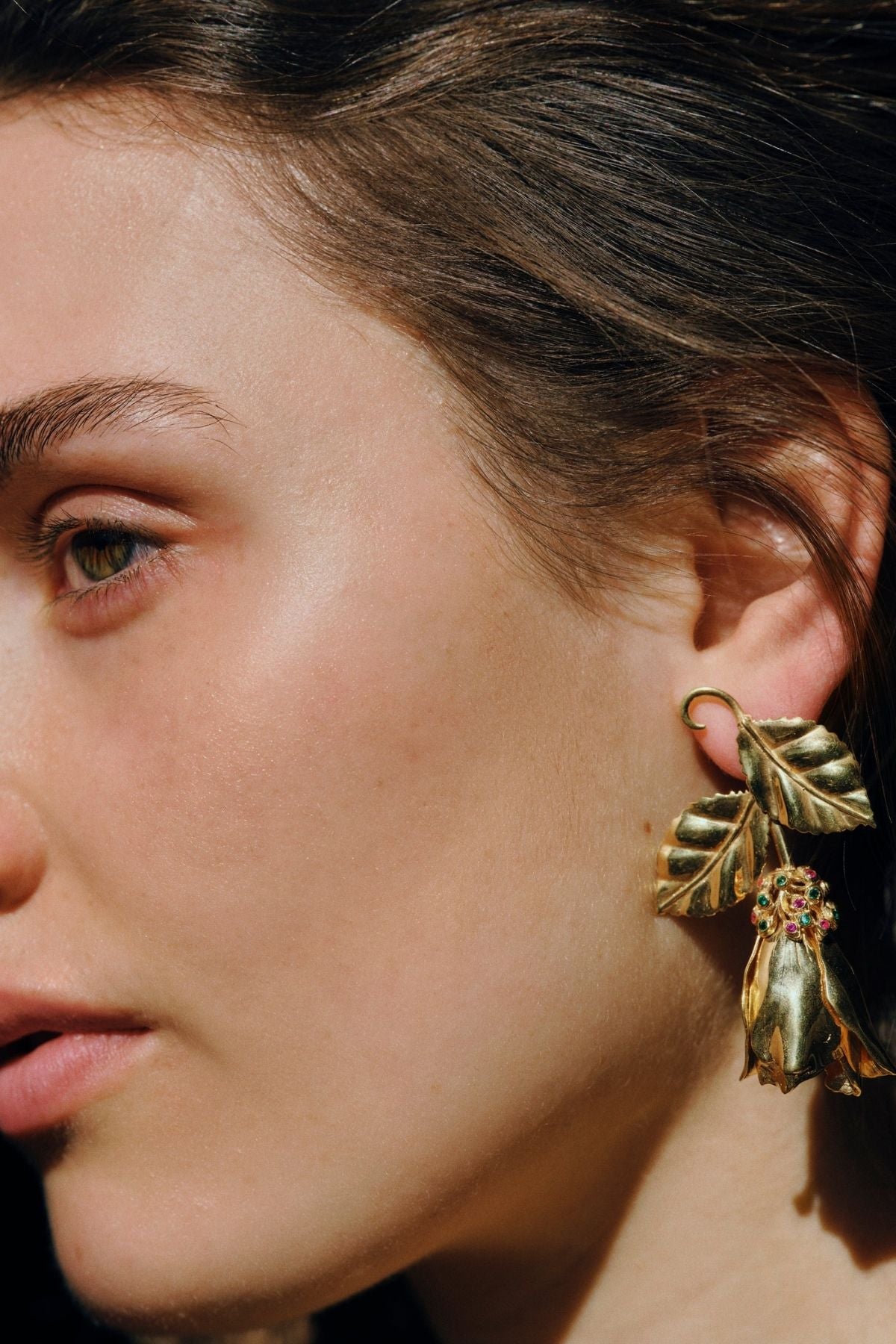 Close-up of a person wearing gold leaf earrings.