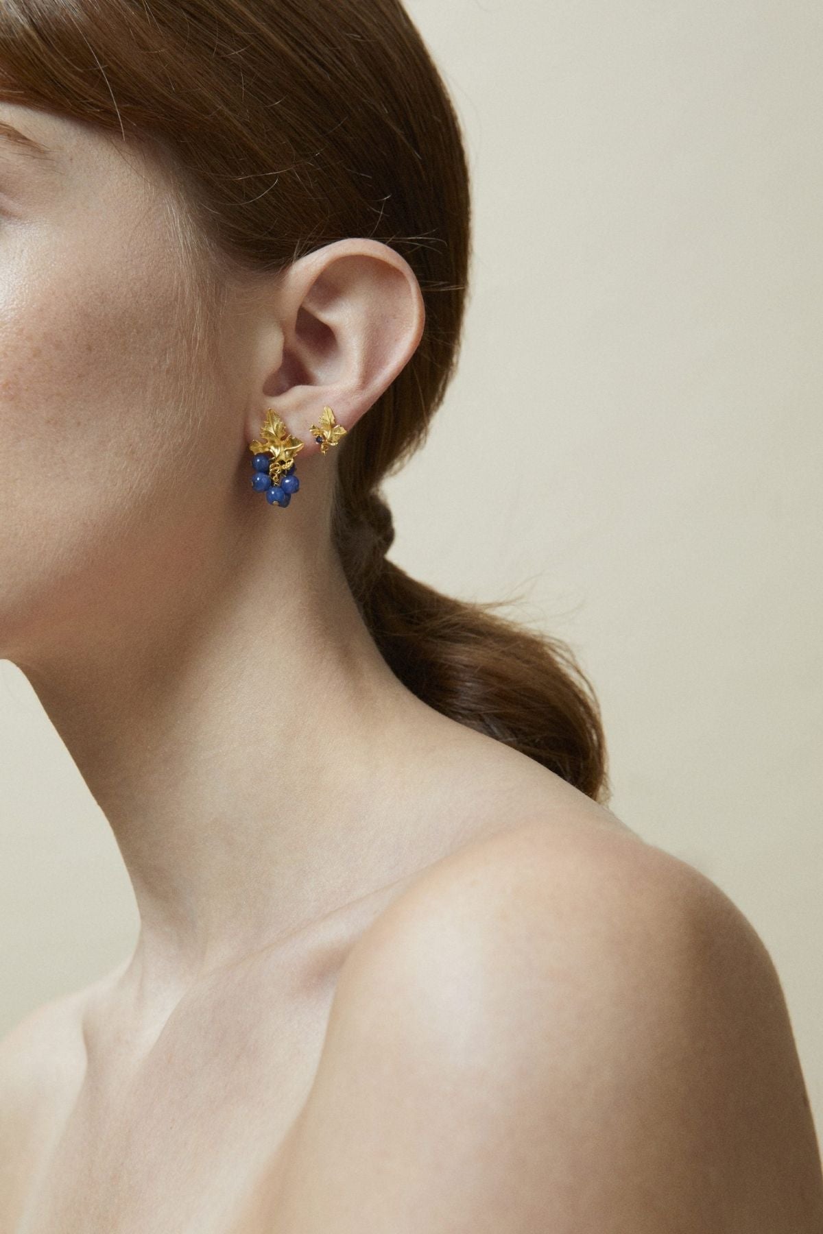 Close-up of a person wearing a pair of earrings with a neutral background
