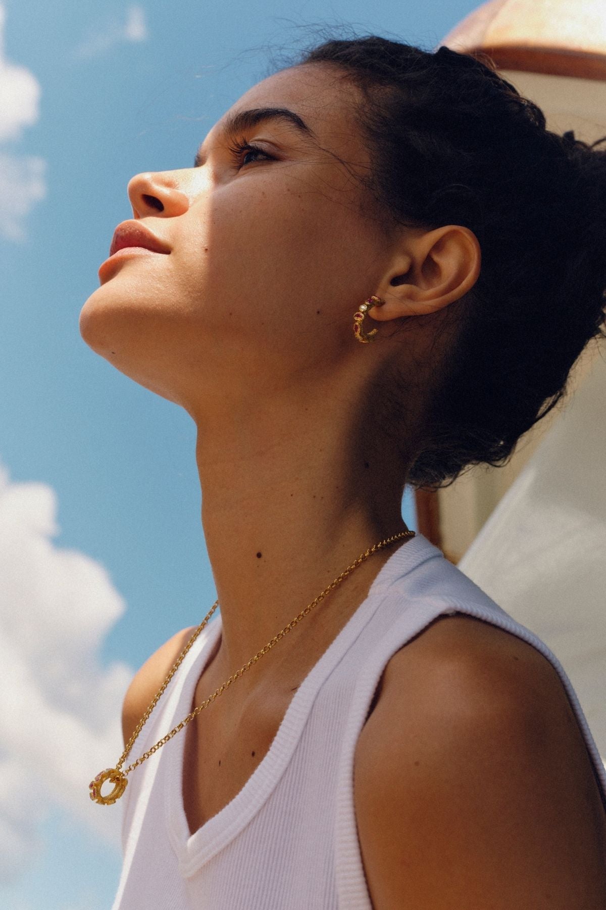 Woman wearing gold jewelry against a blue sky