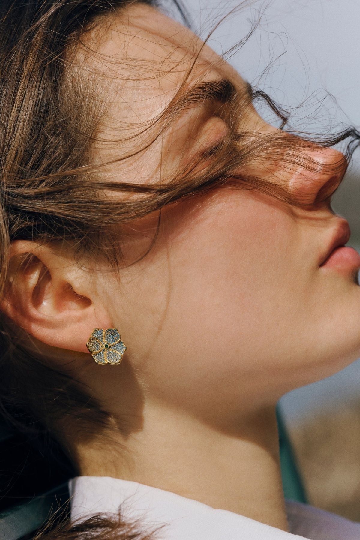 Close-up of a person wearing a floral earring with a blurred background