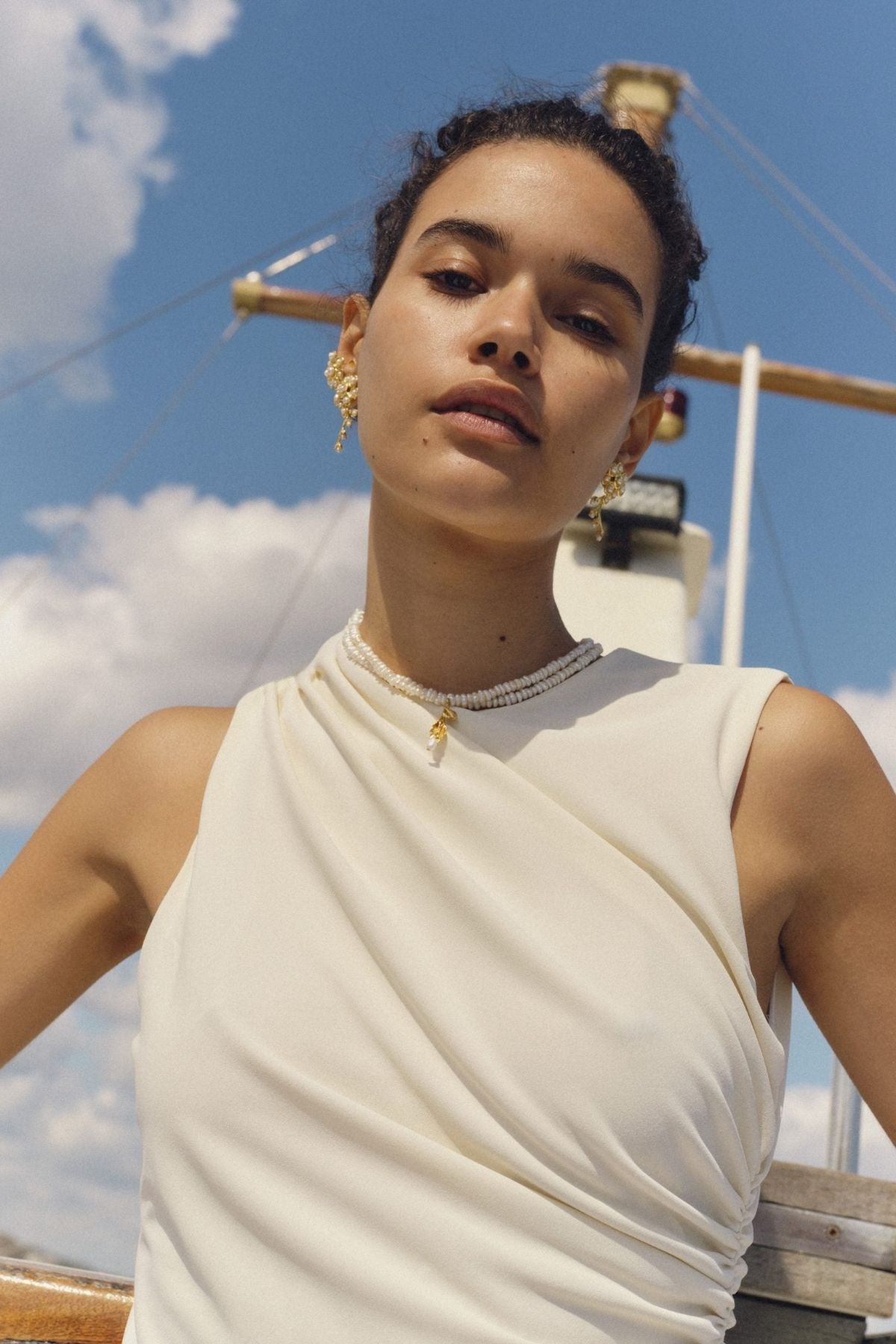 Woman wearing a white sleeveless top with a scenic background