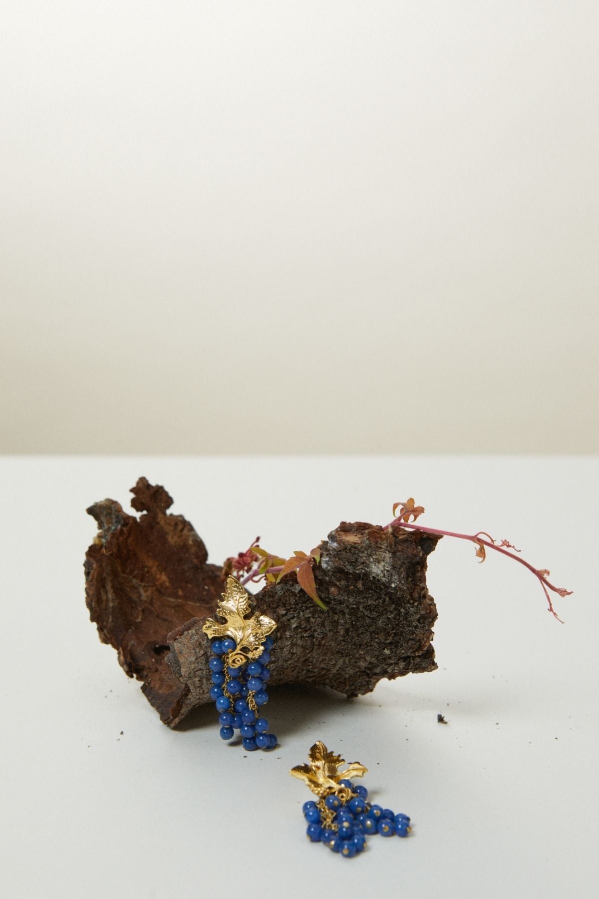 Pair of blue beaded earrings with gold accents on a wooden block against a white background