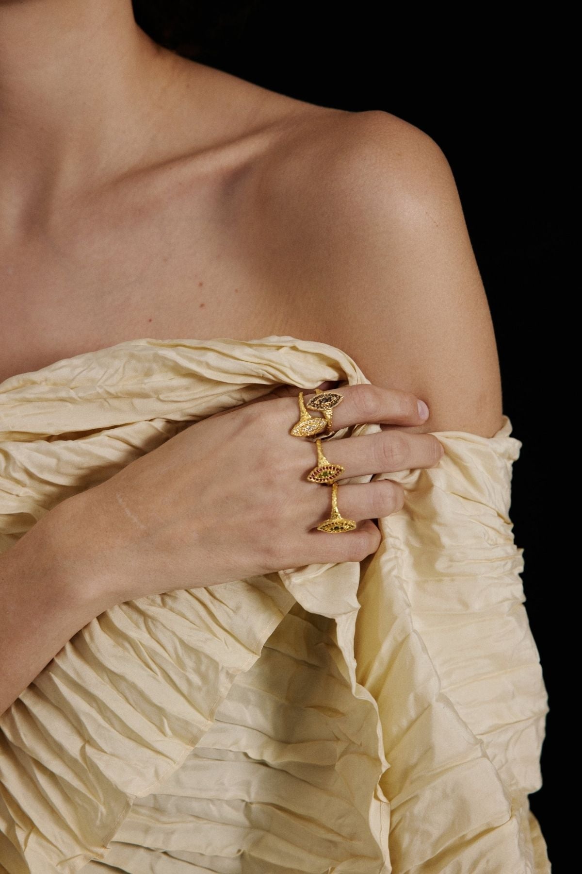 Close-up of a person wearing gold rings on a plain background