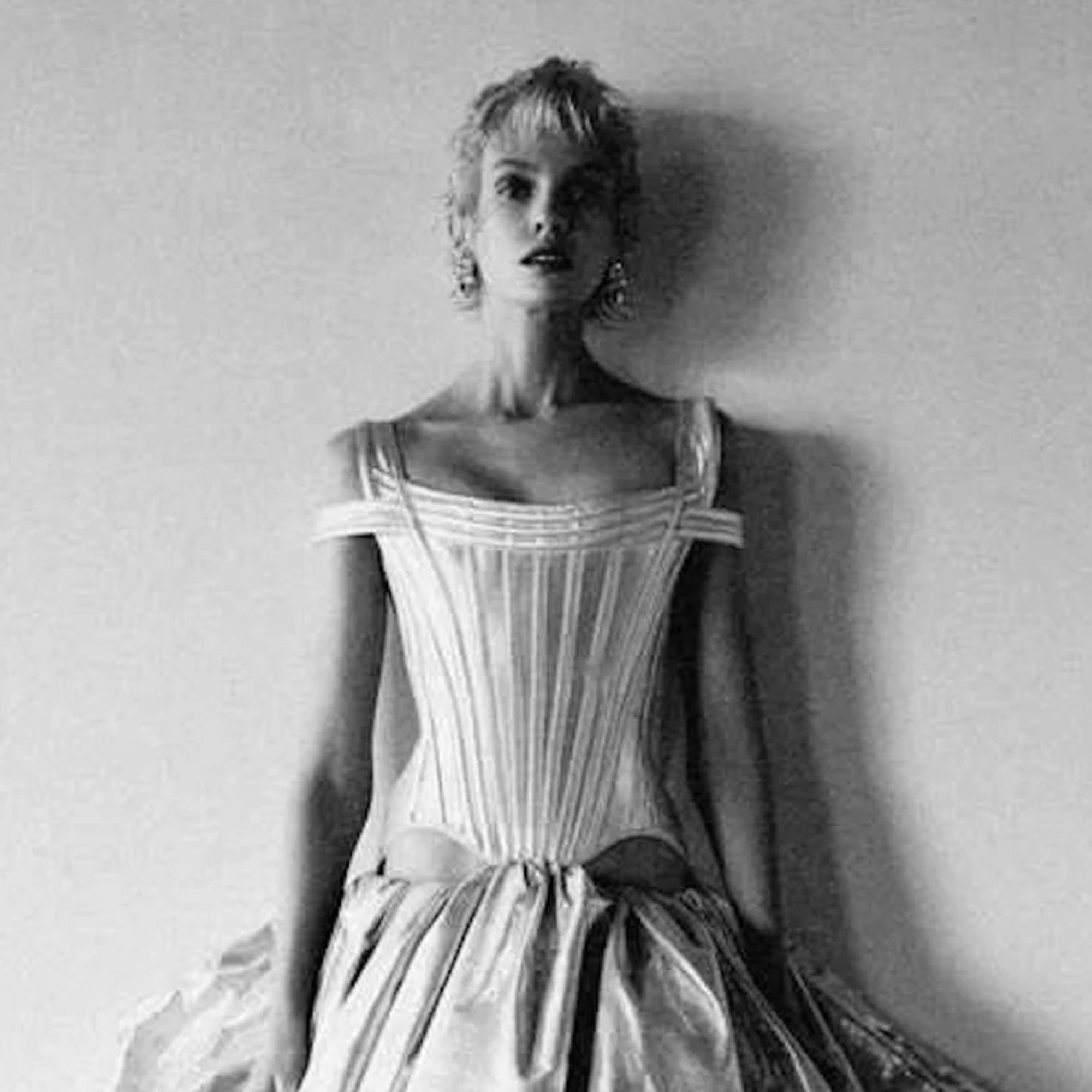 Black and white photo of a woman wearing a vintage dress against a plain background